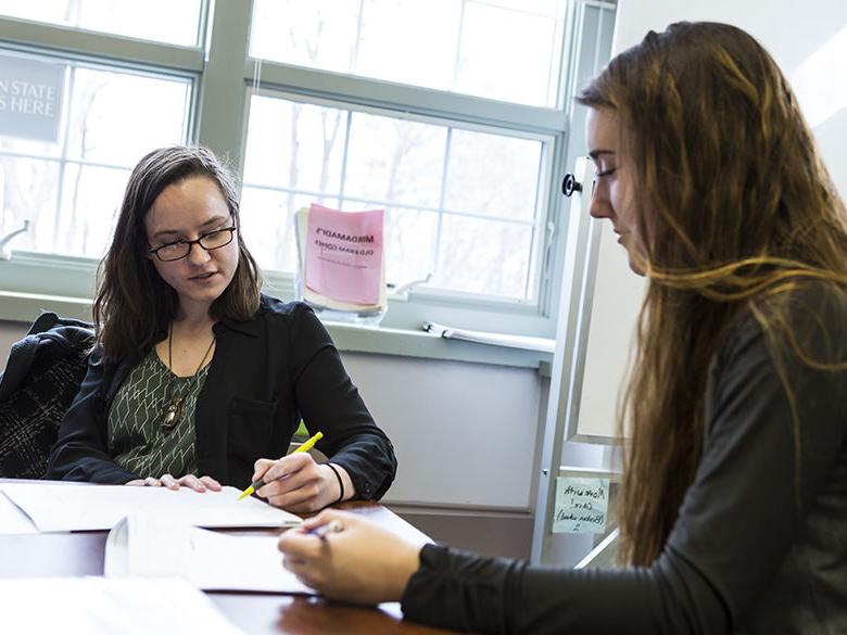 Female student works on paperwork with help from female staff member